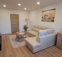 Living room in a three-room apartment with a wooden decor floor and a comfortable sofa.