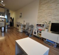 Living room with wood-patterned flooring, kitchen, dining table, and TV cabinet.