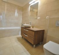 A bathroom in a 3-room apartment with a bathtub, a sink, and a cabinet with a wooden decor.