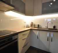 A kitchen in a 3-room apartment with a linear kitchen unit and a floor with a wood decor.