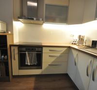 A kitchen in a 3-room apartment with a wooden decor floor and a modern kitchen unit.