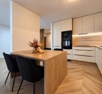 A kitchen in a 3-room apartment with a wooden decor floor and a decorative table.