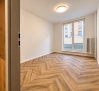 Interior of a 3-room apartment with wood-patterned flooring, white walls, large window.