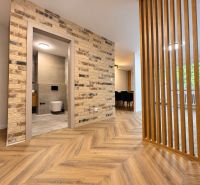 Interior of a 3-room apartment with a wooden decor floor and a brick wall.