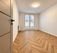 A room in a 3-room apartment with a wood-decor floor and a French window.