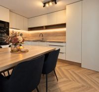 A kitchen in a 3-room apartment with a wooden decor floor and modern furnishings.