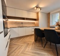A kitchen in a three-room apartment with a wooden decor floor and a dining table.