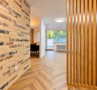Interior of a 3-room apartment with a brick wall and a wooden decor floor.