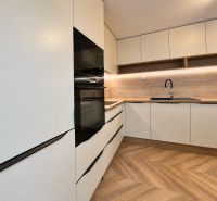 A kitchen unit with white cabinets and wooden decor in a 3-room apartment.
