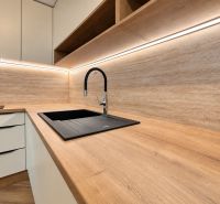 A kitchen in a 3-room apartment with a wooden decor floor and white cabinets.