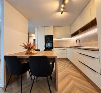 A kitchen in a 3-room apartment with pleasant lighting and a wooden decor floor.