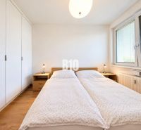 A bright bedroom with a large bed, wardrobe, and wood-decorated floor in a 2-room apartment.