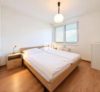 A bedroom in a 2-room apartment with a bed, a nightstand, and a floor with a wooden decor.