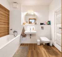Bathroom in a 2-room apartment with a bathtub, sink, and floor with a wooden decor.