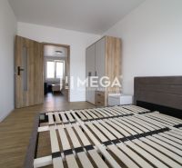 A bedroom in a two-room apartment with a wooden decor floor and simple furnishings.