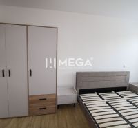 Bedroom in a 2-room apartment with a bed, nightstands, and a wardrobe on a floor with a wooden decor.