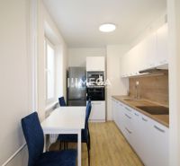 A kitchen with white cabinets and a wood-patterned floor in a 2-room apartment.