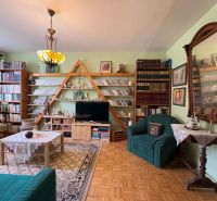 Living room in a 3-room apartment with a wooden decor floor and a rich library.