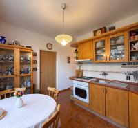 A kitchen in a 3-room apartment with wooden decorations, plates, and a vase with flowers.