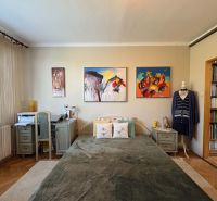 A bedroom in a 3-room apartment with a wooden decor floor and art paintings on the wall.