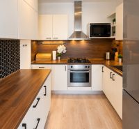 A kitchen in a 2-room apartment with wooden decor and black hexagonal tiles.