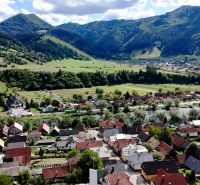 A picturesque panorama of Švošov depicting diverse residential plots with a hilly background.