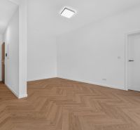 A white interior of a 3-room apartment with wood-patterned flooring and modern lighting.