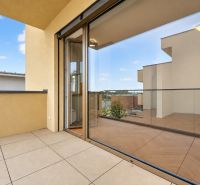 A balcony with a view, glass railing, wooden decor flooring, part of a 3-room apartment.