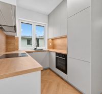 A kitchen in a 3-room apartment with a wood-decor floor and modern appliances.