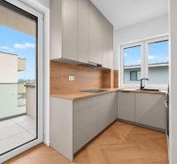 A kitchen in a 3-room apartment with a wooden decor floor, view of the balcony.