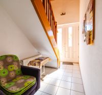 A hallway with a comfortable armchair, stairs, and a door in a family house.
