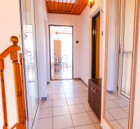 A hallway in a family house with tiles and a mirror, leading to a dining room with a wooden ceiling.