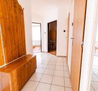 A hallway in a family house with tiles and wooden furniture.
