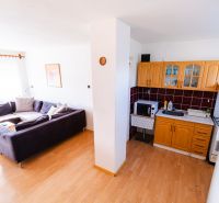 Living room and kitchen in a family house with a corner sofa and kitchen cabinets.
