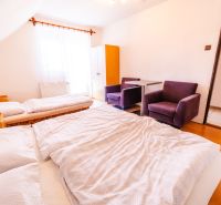 A bedroom in a family house with a double bed, chairs, and a wooden decor floor.