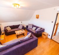 A living room in a family house with a purple couch and a wooden decor floor.