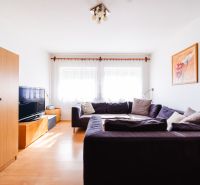 Living room in a family house with a sofa, television, and wooden decor flooring.