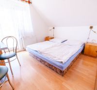 Bedroom in a family house with a double bed, a table, and a floor with a wooden decor.