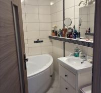 A bathroom in a 2-room apartment with a bathtub, a sink, and white tiles.