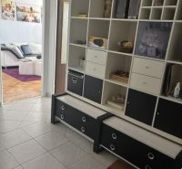 A hallway in a 2-room apartment with a tiled floor and a built-in shelf.