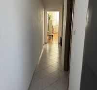 A narrow hallway with a tiled floor leads to a bright room in a two-room apartment.