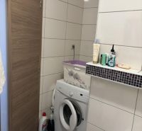 Bathroom in a 2-room apartment with a washing machine and storage space.