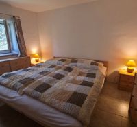 Bedroom in a family house with a double bed, wooden dressers, and lamps.