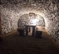 A stone cellar in a family house with wooden benches and a table.
