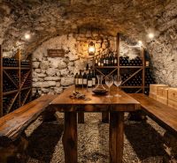 Stone wine cellar with a wooden table and wine racks in a family house.