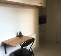 A work corner in a 2-room apartment with a folding table and a shelf.