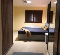 Bedroom in a 2-room apartment with a double bed and a window with dark blinds.