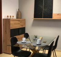 Glass table with four chairs, decorations, and a shelf in a 2-room apartment.