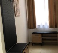 A hallway in a 2-room apartment with benches and a coat rack, light curtains, beige floor.