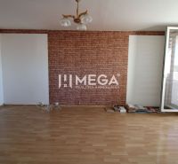 A room with brick cladding, a floor with a wooden decor, and a large window in a 3-room apartment.